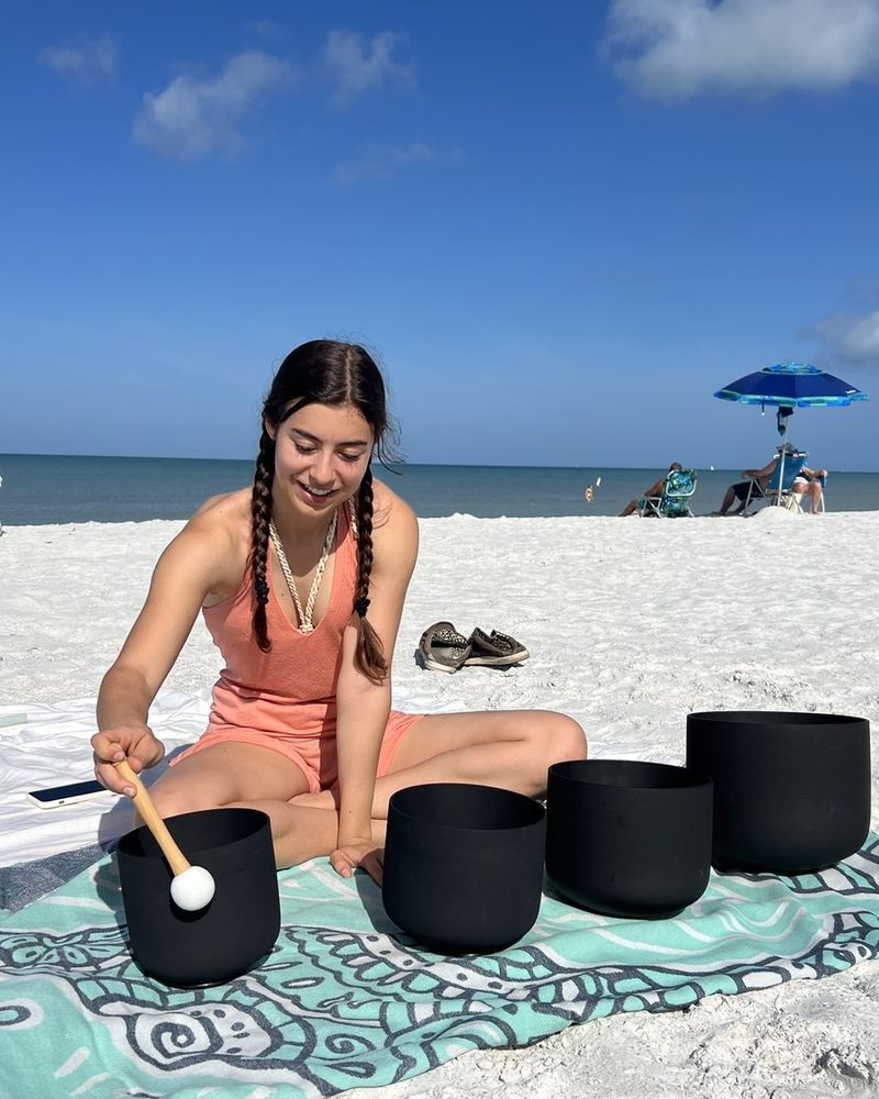 Bella Engelman playing singing bowls on the beach